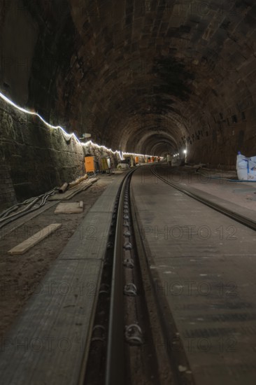 Long stone tunnel with lighting and construction equipment along the track, construction of the