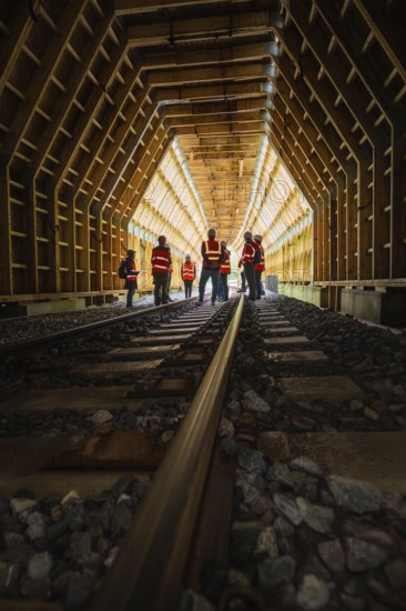 Groups of workers in a wooden railway tunnel, illuminated from the inside, construction of the