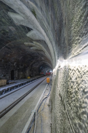 Unfinished tunnelling with exposed cables and rails in a shady environment, construction of the