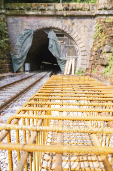 Construction site of a railway with tunnel and steel grid, surrounded by daylight and renovation
