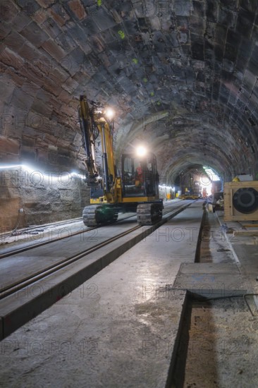 An excavator in an illuminated tunnel on rails, with a depth of perspective in the scene,