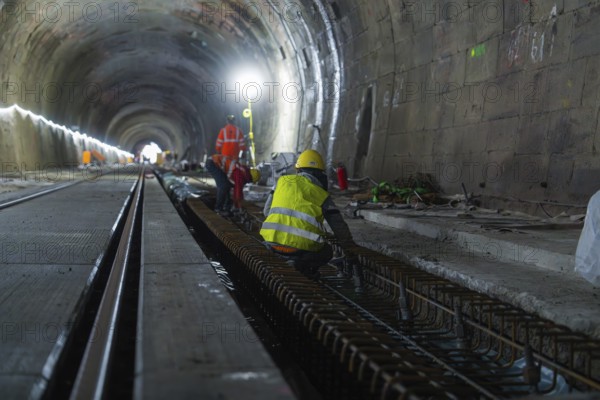 Construction workers in the tunnel working on the tracks. The scene is illuminated by strong light,