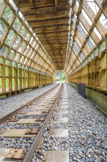 Empty wooden tunnel with view of green landscape through the transparent area, construction of the