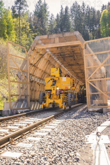 Yellow machine drives through a tunnel surrounded by wood, construction of the Hermann Hesse