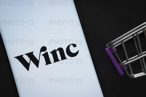 Dhaka, Bangladesh- 03 July 2025: A smartphone displaying the Winc logo next to a miniature shopping