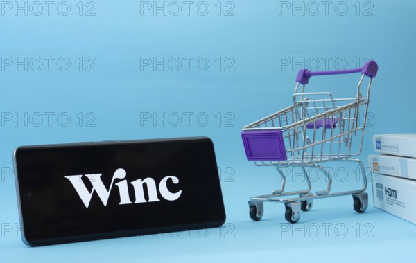 Dhaka, Bangladesh- 03 July 2025: Smartphone with Winc logo next to a small shopping cart and boxes
