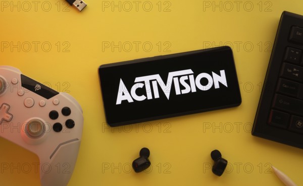 Dhaka, Bangladesh- 23 Sep 2025: Smartphone with Activision logo, game controller, and earbuds on a