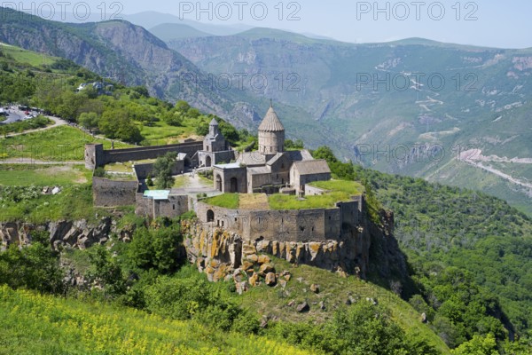 An ancient monastery sits majestically on a hill overlooking a mountainous landscape, Tatev
