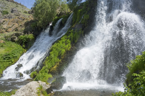 A rushing waterfall flows over moss-covered rocks in a green setting, Shaki Waterfall, Shaki,