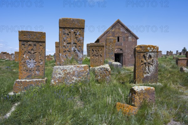 Old gravestones and a chapel in a green cemetery under a bright blue sky, cross stones, the world's