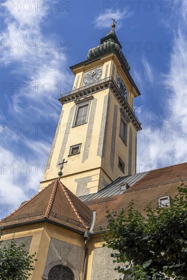 Baroque church tower with clock against a blue sky with light clouds, Old Town Linz Upper Austria