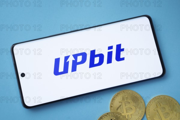 Dhaka, Bangladesh- 19 Sep 2025: Upbit logo on smartphone screen near Bitcoin coin and QR code on