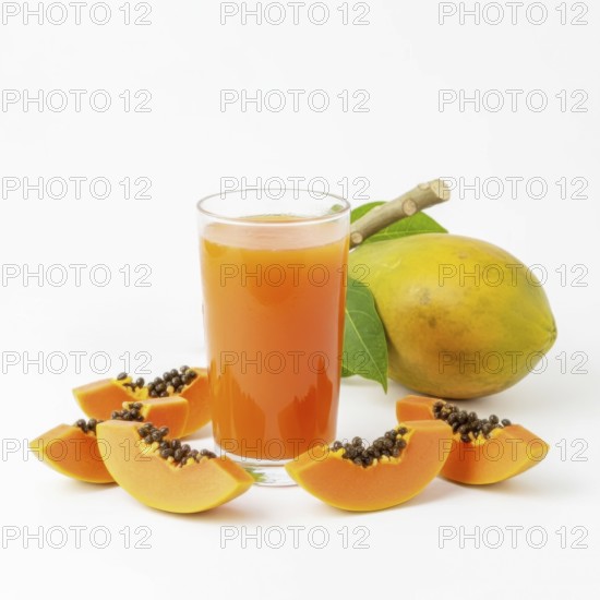A refreshing glass of papaya juice is surrounded by fresh papaya slices and a whole papaya fruit,