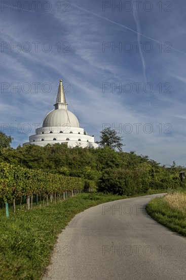 White pagoda surrounded by green nature and meadows under a blue sky, Stupa am Wagram Grafenwörth