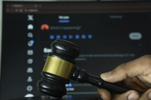 Dhaka, Bangladesh- 20 June 2025: A hand holds a gavel in front of a computer screen displaying X