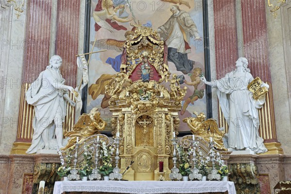 Magnificent baroque altar with golden details and statues, surrounded by ornate frescoes,