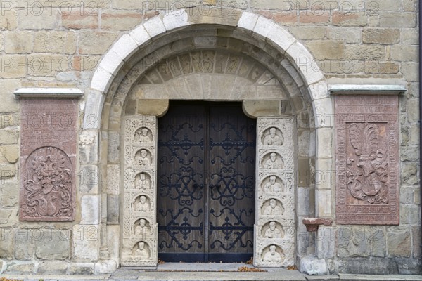 Historic stone door with reliefs and coats of arms, decorated medieval architecture, parish church