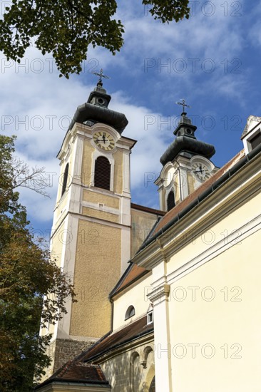 Baroque church towers with clocks rise against a clear blue sky in the afternoon light, St.Stephan