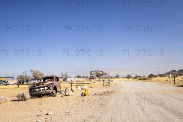 Solitaire's car graveyard in Namibia features rusted vintage cars near small desert buildings, set