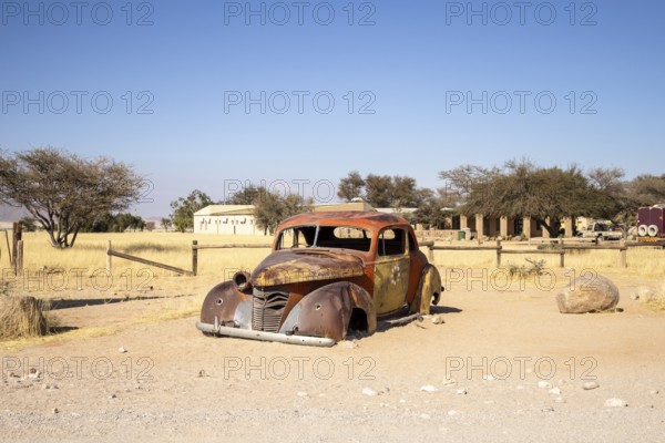 Solitaire's car graveyard in Namibia features rusted vintage cars near small desert buildings, set