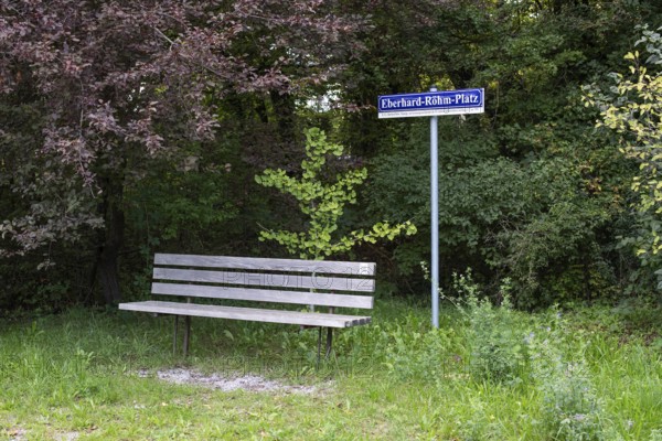 Wooden bench in front of a sign with the inscription Eberhard-Röhm-Platz, square named after a