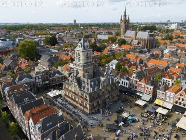 Town hall with tower, surrounded by historic buildings and lively market life, aerial view, town