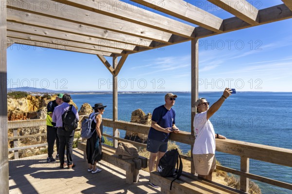 Tourists on the rocky coast of Ponta da Piedade, rugged coastal landscape, right next to Lagos city