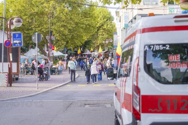 An ambulance parked near a busy market square with a crowd of people, Sindelfingen, Böblingen