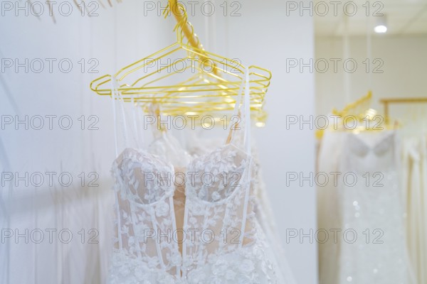 Row of white wedding dresses made of filigree lace presented on yellow hangers, Sindelfingen,