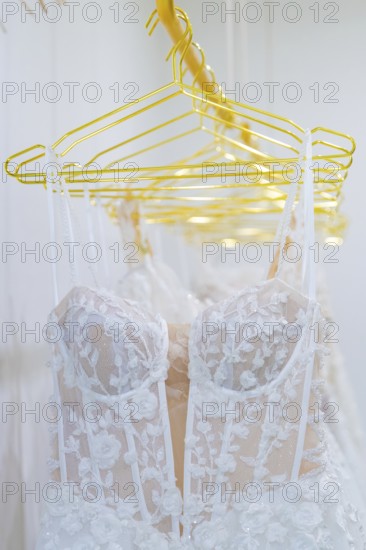 White lace wedding dresses hang elegantly on yellow hangers, Sindelfingen, Böblingen district,
