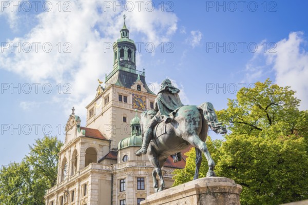 Equestrian statue in front of a magnificent historical building, surrounded by trees and blue sky,