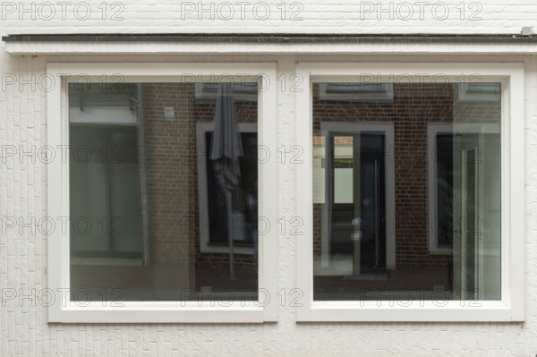 TBorken, NRW, Germany, wo large windows are reflecting a brick building and a parasol on a white