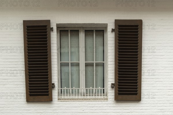 Borken, NRW, Germany, Brown shutters are closed over a window with a white security bar on a white