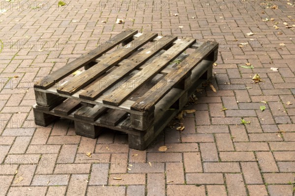 Borken, NRW, Germany, Two weathered wooden pallets are placed on a herringbone brick pavement,