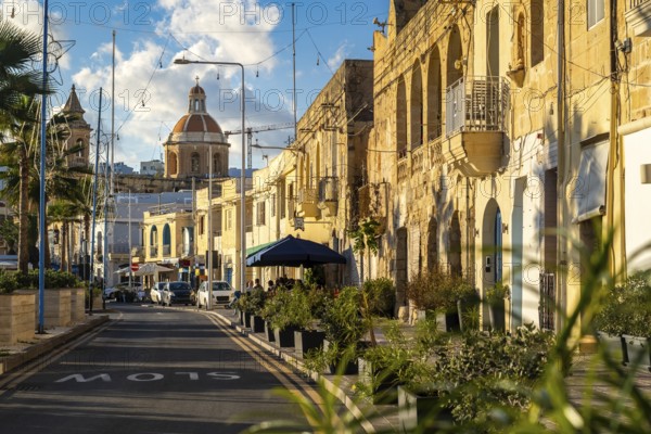 Charming street with limestone building and Saint Mary church at the end, fisherman village of