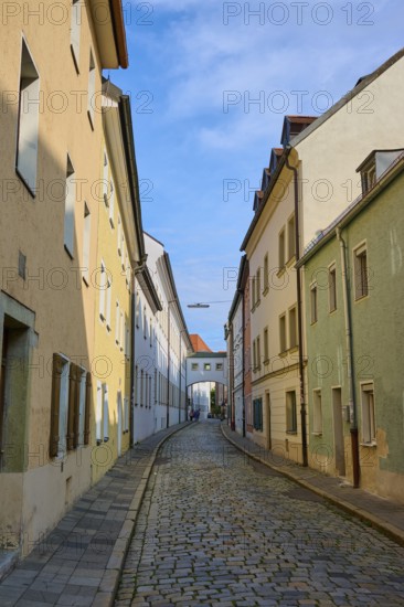 Narrow alley with cobblestones lined with colourful houses under a clear sky, Waffnergasse,