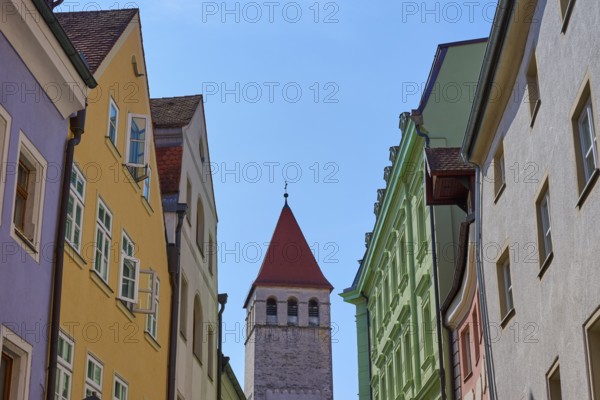 Colourful buildings and church tower along a busy street under a clear sky, Regensburg, Bavaria,