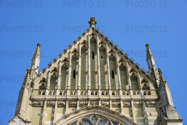 Decorated Gothic façade with window and roof spire under a clear sky, St Peter's Cathedral,
