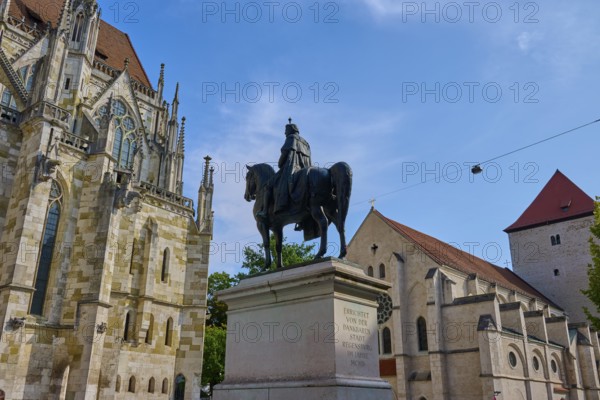 Equestrian statue in front of a historic church under a blue sky, St Peter's Cathedral, Regensburg,