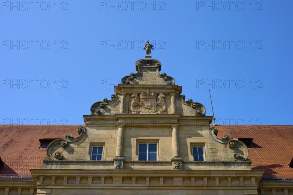Baroque building front with sculptures and decorative stone ornaments under a clear sky, district