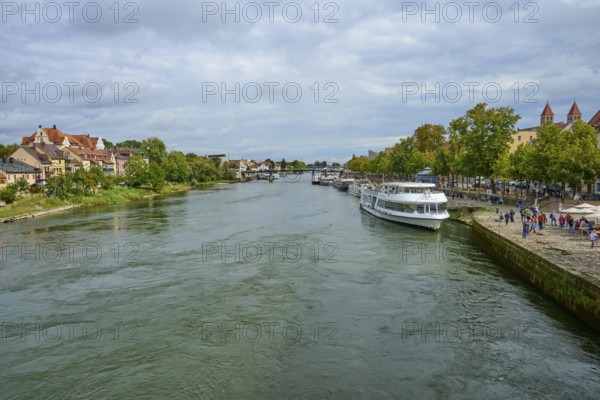 River landscape with boats and houses along the shore under a cloudy sky, Danube, Regensburg,