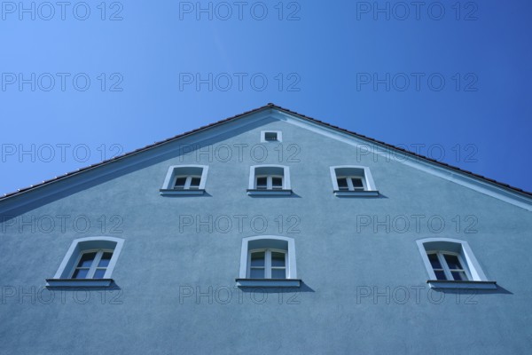 Blue house with several windows and sloping roof in front of a bright blue sky, Regensburg,