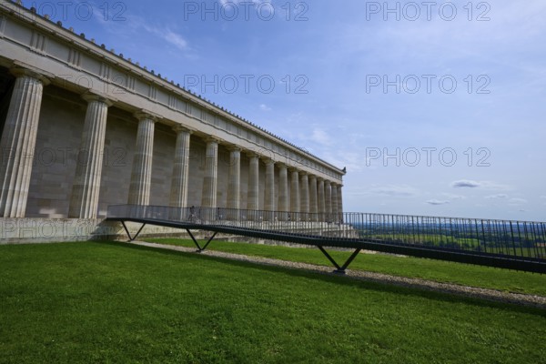 Historic columned building next to a green area under a clear blue sky, Walhalla, Donaustauf,