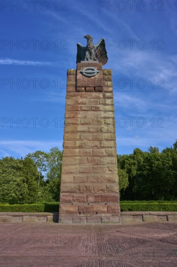 Massive memorial with eagle at the top, surrounded by trees, under a clear blue sky. Means strength
