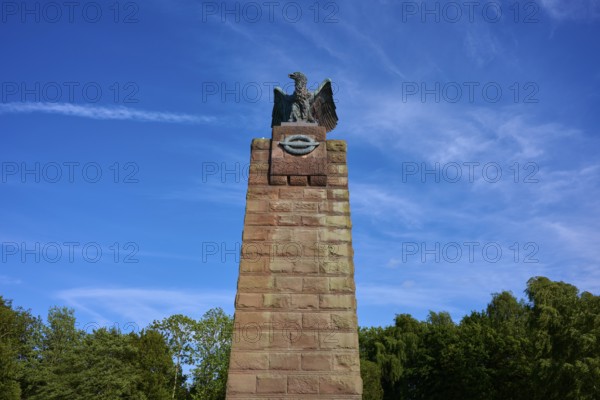 Massive stone monument with eagle, under a bright blue sky. Impression of grandeur and freedom in