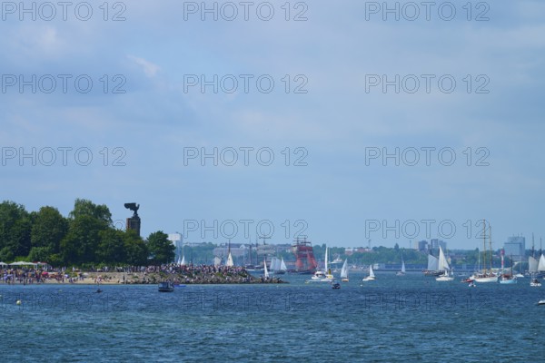 Boats and yacht on the sea near a tree-covered shore with people, Windjammer Parade Kiel 2025,