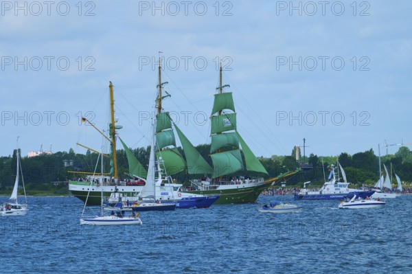 A large sailing ship with green sails Alexander von Humbold 2 and other boats on blue water,