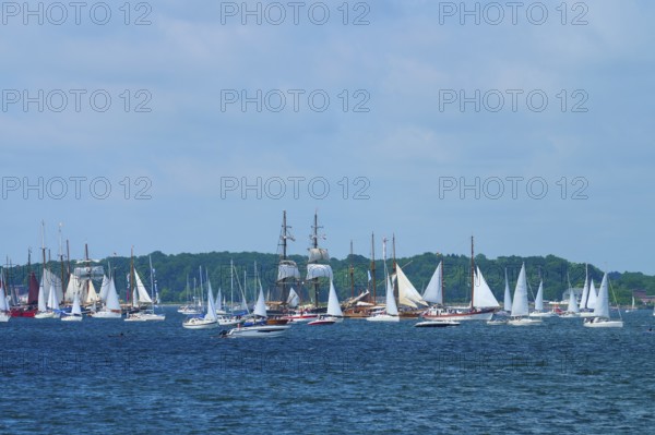Many sailing boats and a large sailing ship on the sea under a blue sky with clouds, Windjammer