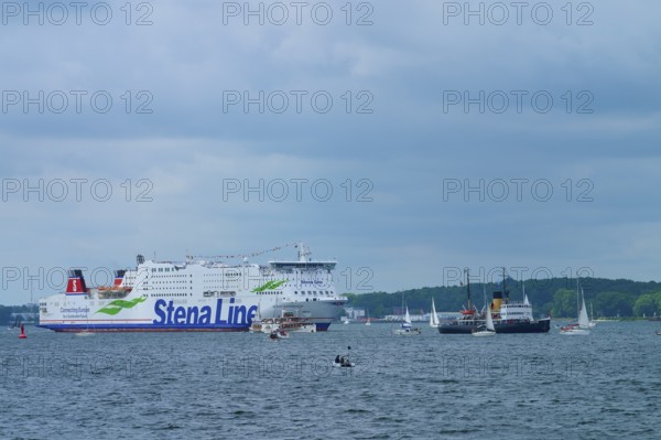 Stena Line ferry and historic ship in a sea travelled by sailing boats with cloudy sky, Windjammer
