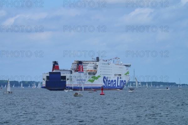 Large ferry on the sea surrounded by sailing boats under a blue sky, Windjammer Parade Kiel 2025,